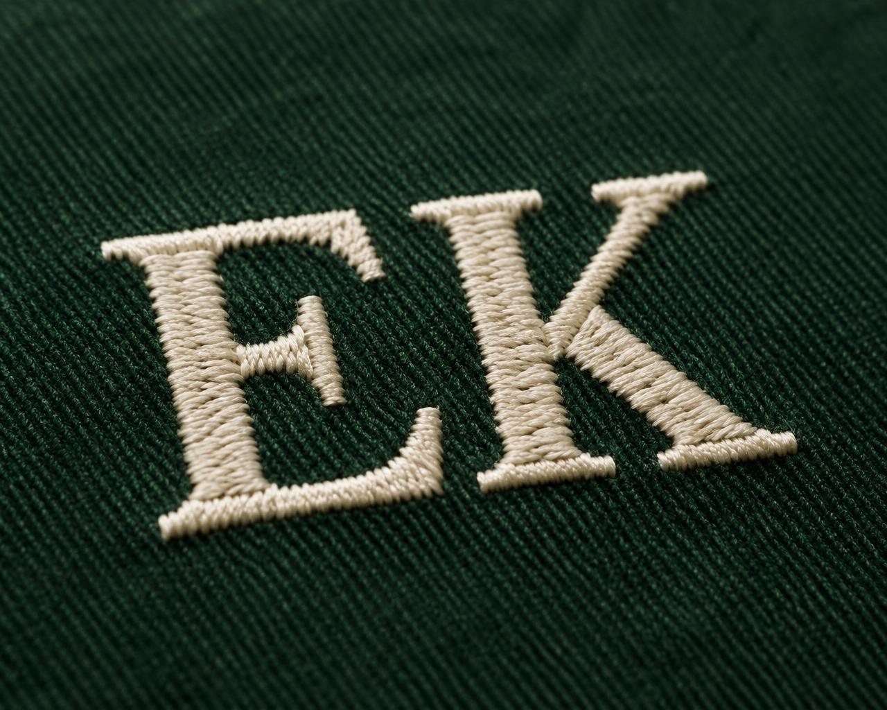 Close-up of cream EK embroidery on forest green cotton